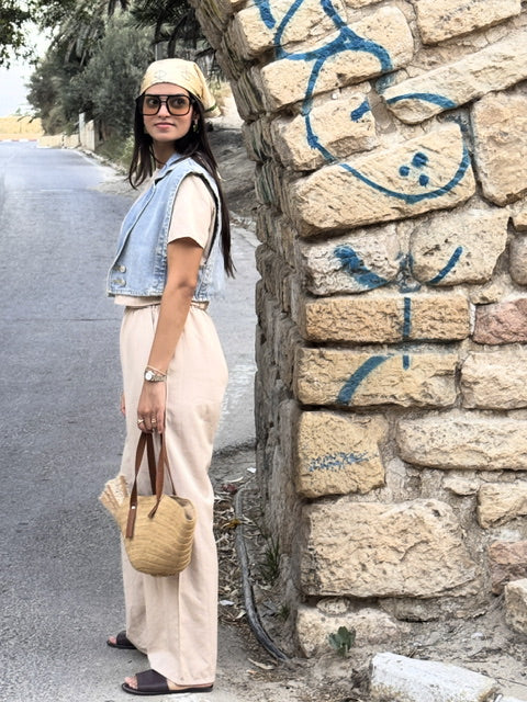 Woman standing next to a stone wall with graffiti on a road